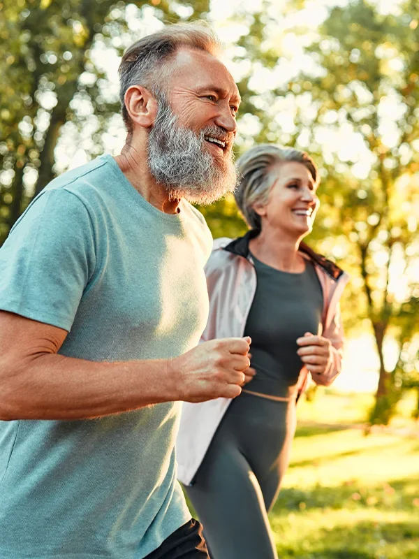 happy middle-aged man & woman running outside
